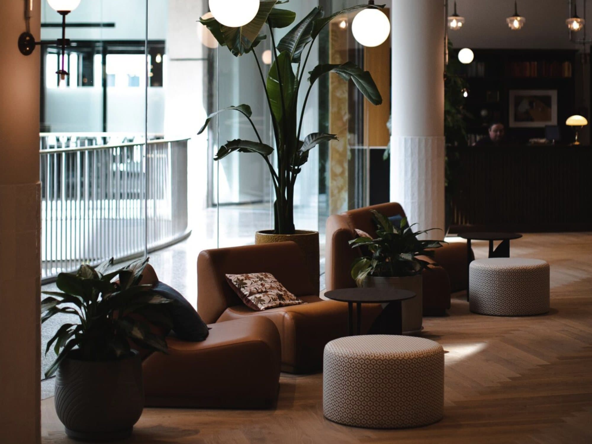 The lounge at our Düsseldorf location: leather armchairs, tall plants and globe lights