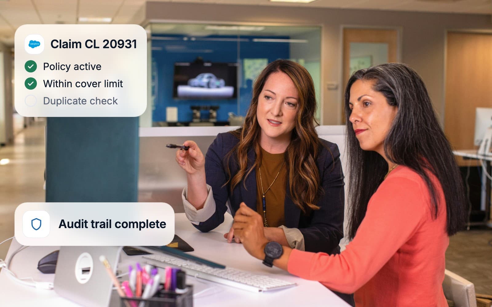 Two colleagues reviewing a claim at a desk while the rule checks run