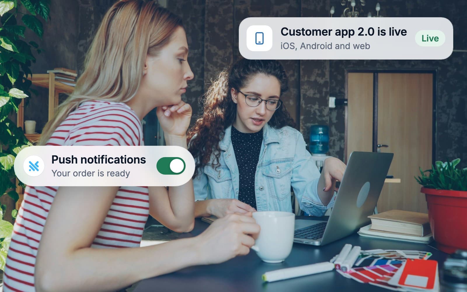 Two colleagues using their company's new app on a laptop in a cafe